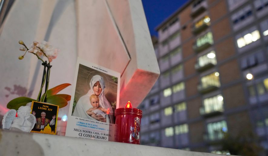 An image of Pope Leo XIV rests at the base of a statue of the late Pope John Paul II outside the Agostino Gemelli Polyclinic, where Leo is hospitalized for surgery to remove a lung nodule, in Rome, Tuesday, Oct. 13, 2026. (AP Photo/Gregorio Borgia)