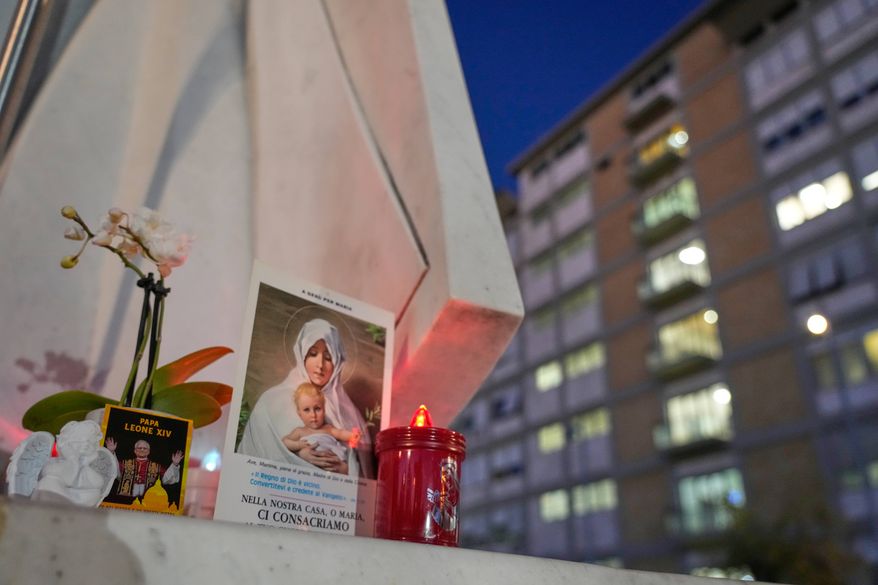 An image of Pope Leo XIV rests at the base of a statue of the late Pope John Paul II outside the Agostino Gemelli Polyclinic, where Leo is hospitalized for surgery to remove a lung nodule, in Rome, Tuesday, Oct. 13, 2026. (AP Photo/Gregorio Borgia)