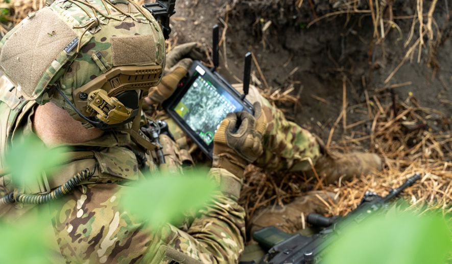 A soldier in tactical gear operates a control tablet in the field. File photo credit: seeasign via Shutterstock.