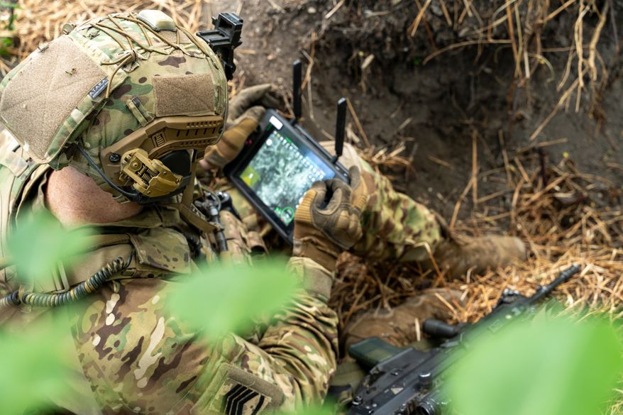 A soldier in tactical gear operates a control tablet in the field. File photo credit: seeasign via Shutterstock.