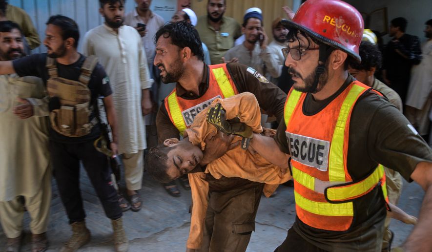 Rescue workers carry an injured boy after rescuing him from the rubble of a roof collapse at a private school, in Peshawar, Pakistan, Thursday, Oct. 15, 2026. (AP Photo/Muhammad Zubair)