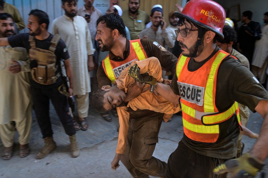Rescue workers carry an injured boy after rescuing him from the rubble of a roof collapse at a private school, in Peshawar, Pakistan, Thursday, Oct. 15, 2026. (AP Photo/Muhammad Zubair)