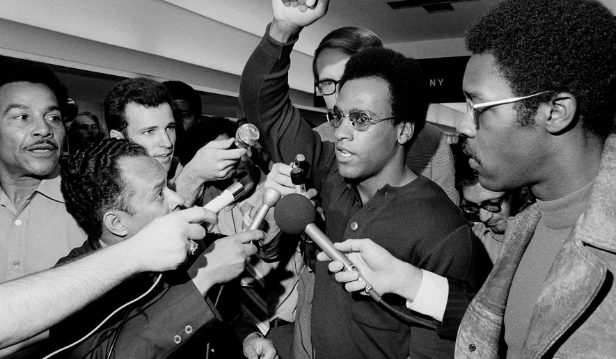 FILE - Huey Newton, Black Panther Party minister of defense, raises his arm as he is surrounded by the press at Philadelphia's International Airport, Sept. 4, 1970, upon his arrival for a convention in Philadelphia. (AP Photo/Rusty Kennedy, File)