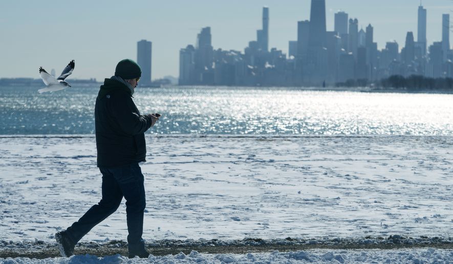 FILE - A person walks near the snow-covered sand at Lake Michigan in Chicago, Jan. 28, 2026. (AP Photo/Nam Y. Huh, File)