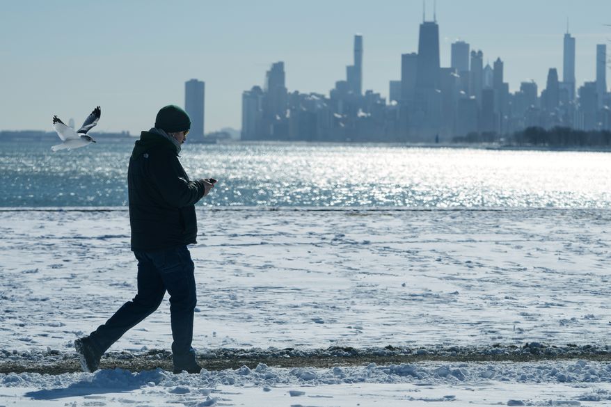 FILE - A person walks near the snow-covered sand at Lake Michigan in Chicago, Jan. 28, 2026. (AP Photo/Nam Y. Huh, File)
