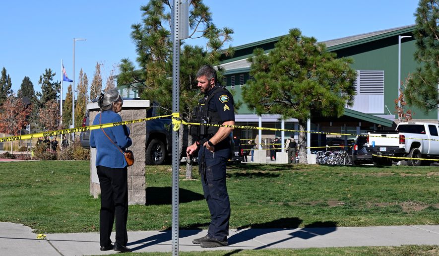 A woman talks to a policeman outside Silver Rail Elementary school, where a shooting took place, on Thursday, Oct. 15, 2026 in Bend, Ore. (AP Photo/Joe Kline)