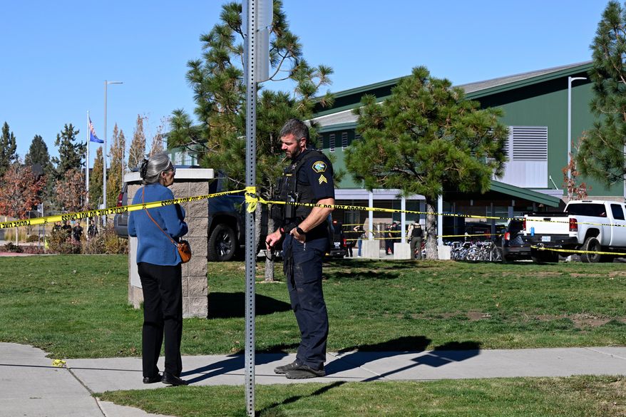 A woman talks to a policeman outside Silver Rail Elementary school, where a shooting took place, on Thursday, Oct. 15, 2026 in Bend, Ore. (AP Photo/Joe Kline)