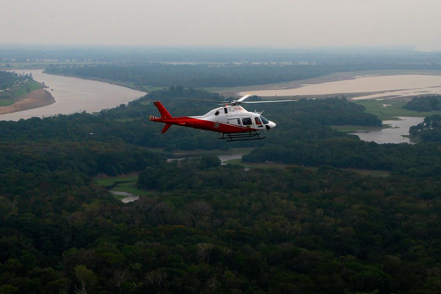 A helicopter from Brazil's environmental agency flies over an area of the Amazon rainforest during a wildfire-fighting operation in Autazes, Amazonas state, Brazil, Thursday, Oct. 15, 2026. (AP Photo/Edmar Barros)