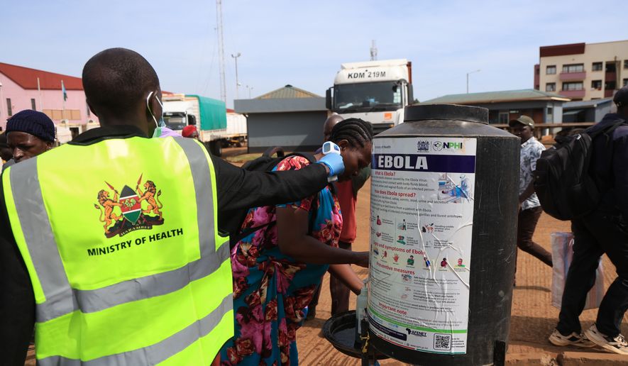 People disinfect their hands as a Kenyan health worker checks the temperatures of travelers crossing from Uganda to Kenya as part of measures to contain the spread of Ebola virus, in Busia, Kenya, Thursday, Oct. 15, 2026. (AP Photo/Andrew Kasuku)