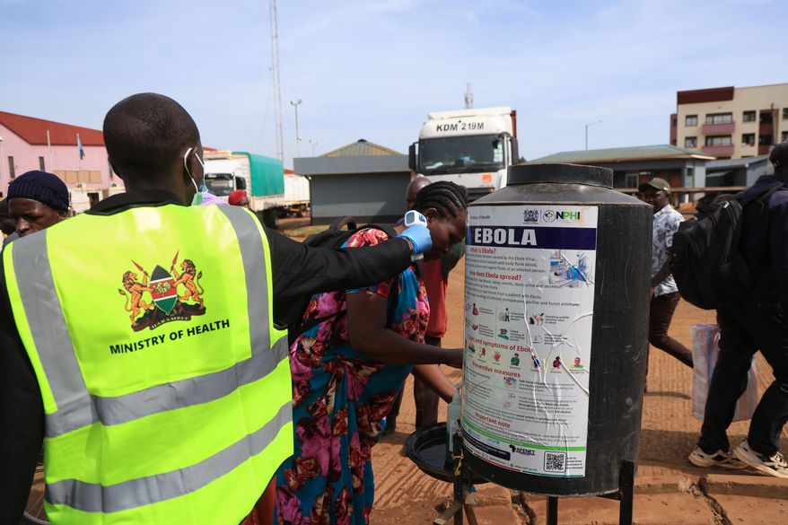 People disinfect their hands as a Kenyan health worker checks the temperatures of travelers crossing from Uganda to Kenya as part of measures to contain the spread of Ebola virus, in Busia, Kenya, Thursday, Oct. 15, 2026. (AP Photo/Andrew Kasuku)