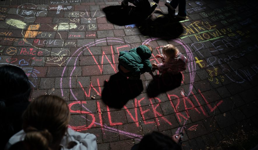 Children draw with chalk during a candlelight vigil at Drake Park following a deadly shooting at Silver Rail Elementary School in Bend, Ore. on Thursday, Oct. 15, 2026. (Eli Imadali/Oregon Public Broadcasting via AP)
