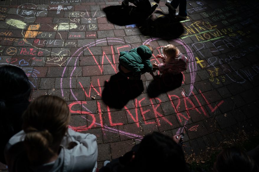 Children draw with chalk during a candlelight vigil at Drake Park following a deadly shooting at Silver Rail Elementary School in Bend, Ore. on Thursday, Oct. 15, 2026. (Eli Imadali/Oregon Public Broadcasting via AP)