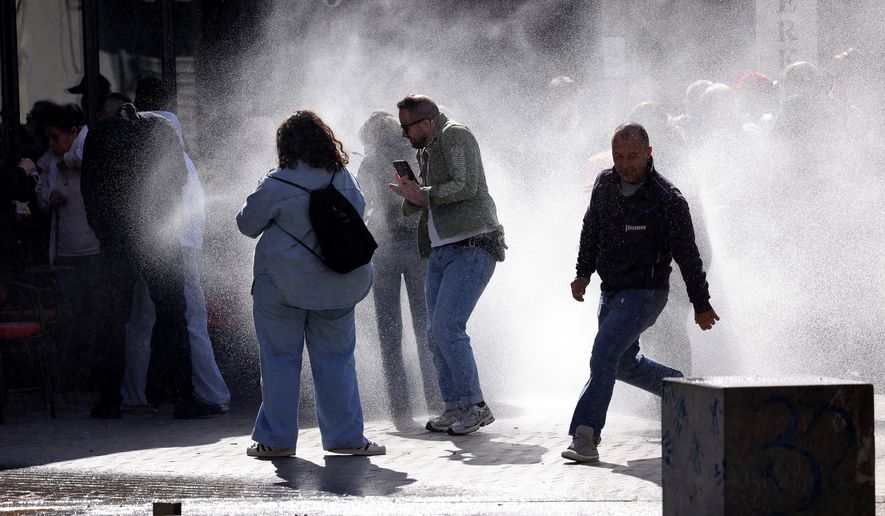 Protesters run from water sprayed by police water cannons during an anti-government demonstration outside the Education Ministry, in Tirana, Albania, Saturday, Oct. 17, 2026. (AP Photo/Hameraldi Agolli)
