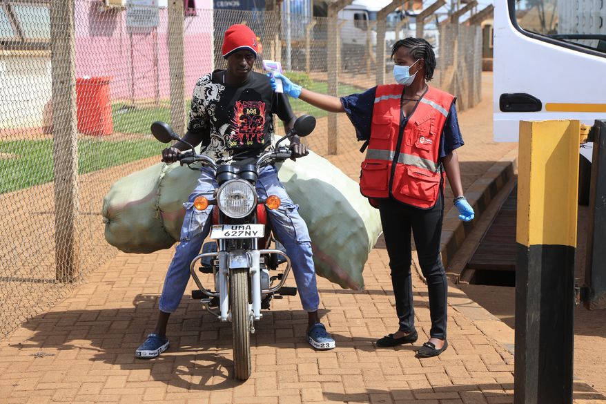 A Kenyan health worker checks the temperatures of travelers crossing from Uganda to Kenya as part of measures to contain the spread of Ebola virus, in Busia, Kenya, Thursday, Oct. 15, 2026. (AP Photo/Andrew Kasuku)