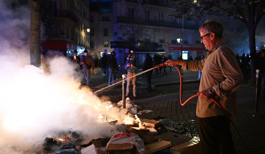 A man tries to extinguish a fire during clashes between protesters and police in Paris, Sunday, Oct. 18, 2026. (AP Photo/Emma Da Silva)