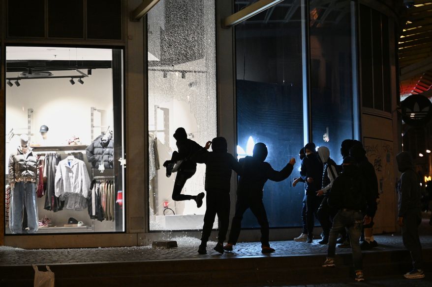 Youths break a store window during clashes between protestors and police in Paris, Sunday, Oct. 18, 2026. (AP Photo/Emma Da Silva)