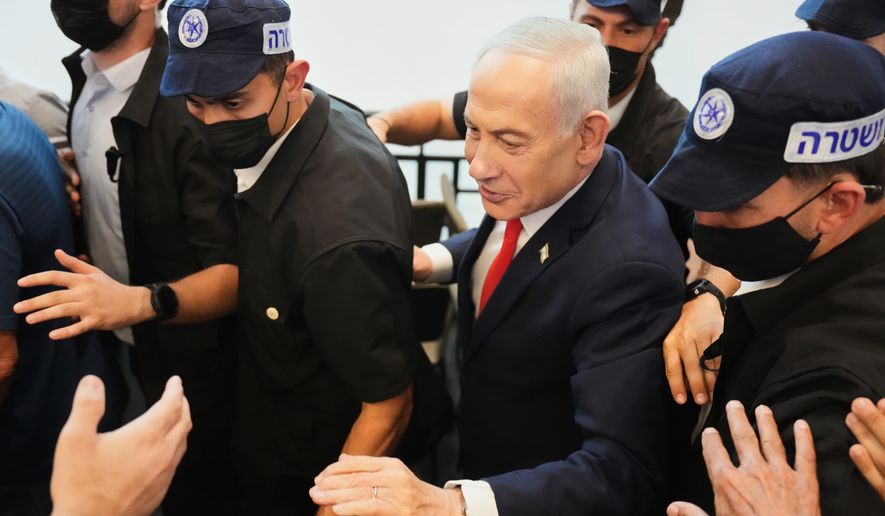 Israeli Prime Minister Benjamin Netanyahu, leader of the Likud party, gestures to supporters as security personnel surround him while he campaigns ahead of the country's general election at a shopping mall in Ramla, Israel, Monday, Oct. 19, 2026. (AP Photo/Ariel Schalit)
