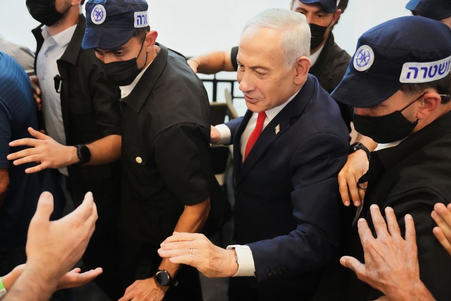 Israeli Prime Minister Benjamin Netanyahu, leader of the Likud party, gestures to supporters as security personnel surround him while he campaigns ahead of the country's general election at a shopping mall in Ramla, Israel, Monday, Oct. 19, 2026. (AP Photo/Ariel Schalit)