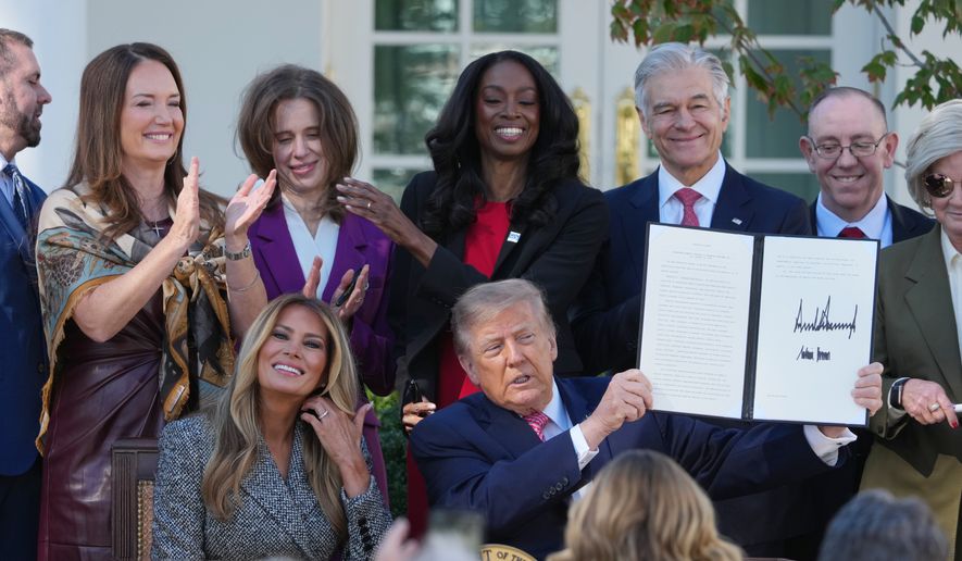 President Donald Trump, with first lady Melania Trump, holds a signed executive order, during an event about women's health, in the Rose Garden of the White House, Monday, Oct. 19, 2026, in Washington. (AP Photo/Mark Schiefelbein)