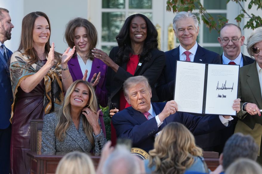 President Donald Trump, with first lady Melania Trump, holds a signed executive order, during an event about women's health, in the Rose Garden of the White House, Monday, Oct. 19, 2026, in Washington. (AP Photo/Mark Schiefelbein)
