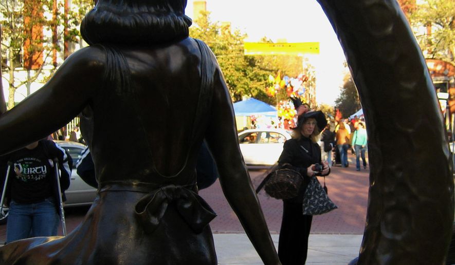 A woman dressed as a witch is framed by a statue in downtown Salem of Samantha Stevens, the witch on the TV show "Bewitched." The statue overlooks one of the main thoroughfares in Salem and is across the street from the pedestrian mall lined with booths selling Halloween-themed wares. (AP Photo/Lisa Marie Pane)