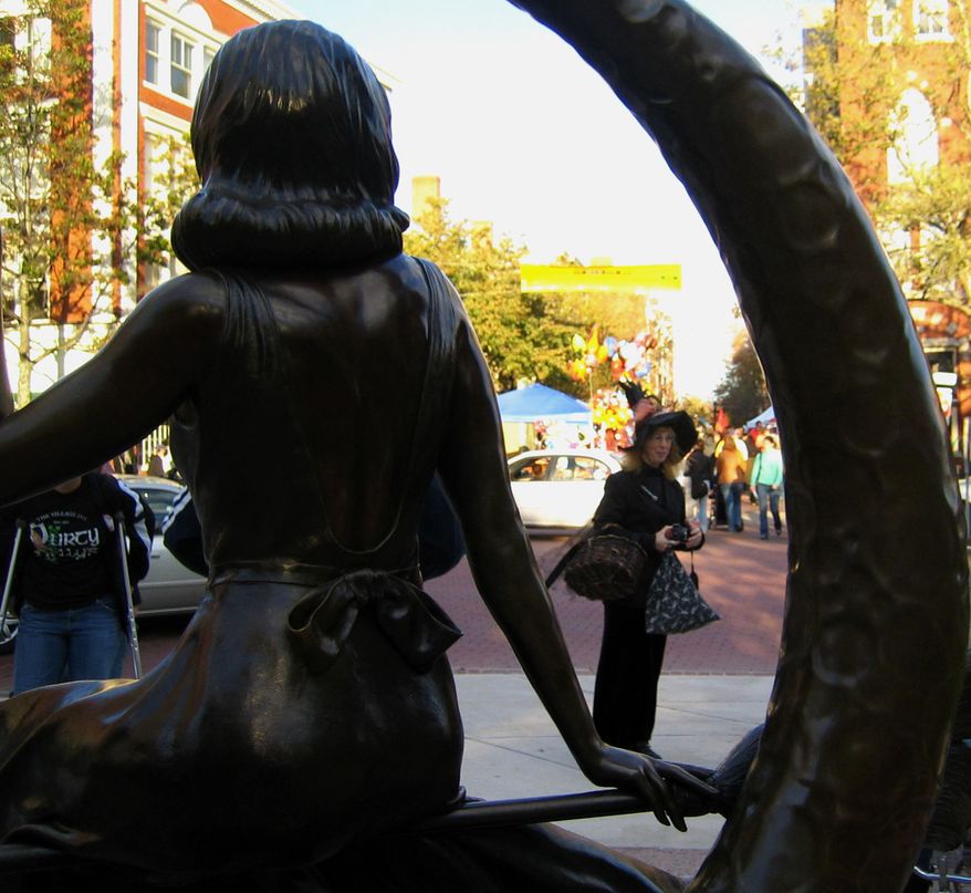 A woman dressed as a witch is framed by a statue in downtown Salem of Samantha Stevens, the witch on the TV show "Bewitched." The statue overlooks one of the main thoroughfares in Salem and is across the street from the pedestrian mall lined with booths selling Halloween-themed wares. (AP Photo/Lisa Marie Pane)