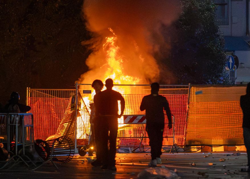 A fire burns following clashes between police and "Italia in Piazza" protesters in front of the Milan Cathedral in Milan, Italy, on Saturday, Oct. 17, 2026. (Stefano Porta/LaPresse via AP)