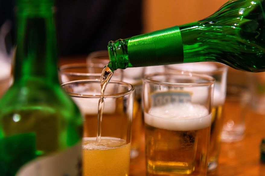 Pouring beer from a bottle into a glass. File photo credit: SUNGMOON HAN via Shutterstock.