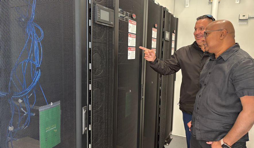 Wiikwemkoong's Chief Technology Officer Michael McCormick, right, and a worker inspect the community's data center in Wiikwemkoong, Ontario, Canada, July 22, 2026. (AP Photo/Kelvin Chan)
