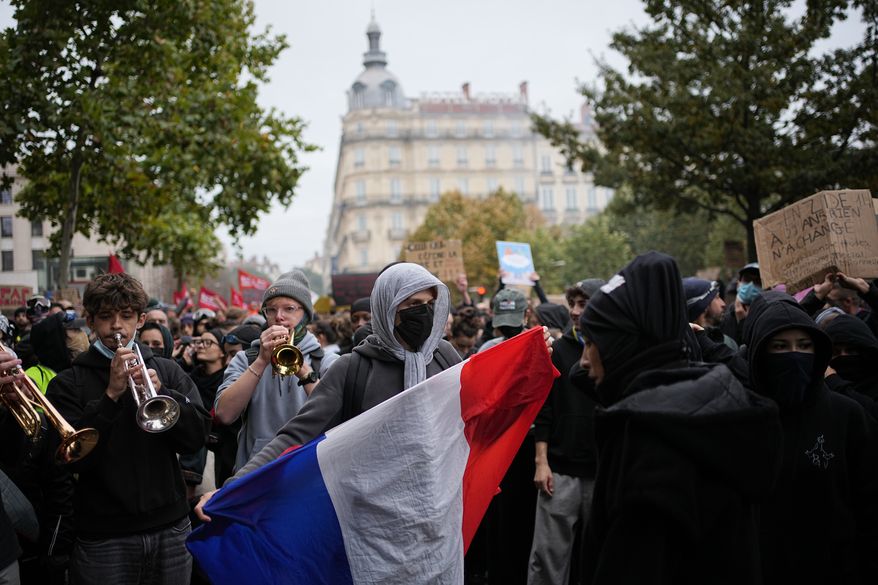A protesters holds a French flag during a demonstration against rising living costs, joining students' grievances, in Lyon, France, Saturday, Oct. 17, 2026. (AP Photo/Laurent Cipriani)