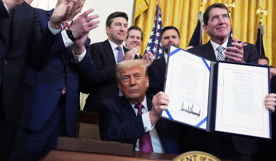 President Donald Trump holds up the signed GENIUS Act, a bill that regulates stablecoins, a type of cryptocurrency, in the East Room of the White House, July 18, 2025, in Washington. (AP Photo/Evan Vucci, File)