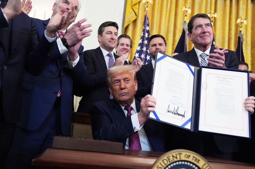 President Donald Trump holds up the signed GENIUS Act, a bill that regulates stablecoins, a type of cryptocurrency, in the East Room of the White House, July 18, 2025, in Washington. (AP Photo/Evan Vucci, File)