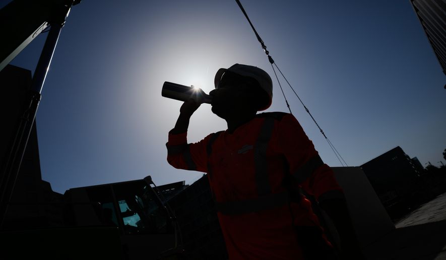 A worker drinks water on a construction site during high temperatures in Boulogne Billancourt, outside Paris, June 24, 2026. (AP Photo/Christophe Ena)