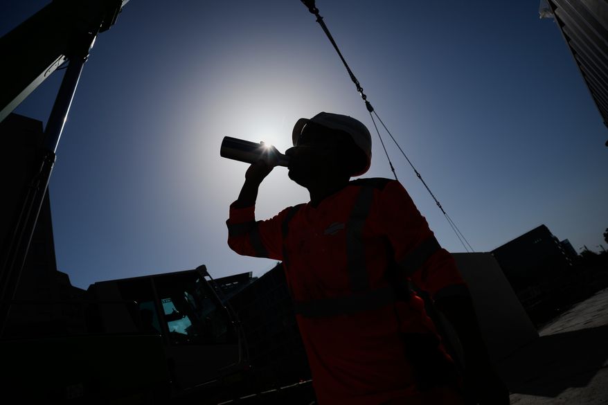 A worker drinks water on a construction site during high temperatures in Boulogne Billancourt, outside Paris, June 24, 2026. (AP Photo/Christophe Ena)