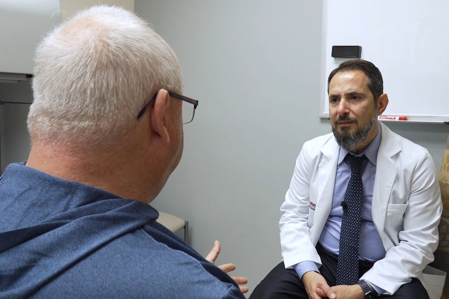 In this image made from video, Tony Hout, left, talks with Dr. Hussein Tawbi at UT MD Anderson Cancer Center in Houston, Monday, Oct. 19, 2026. (AP Photo/Lekan Oyekanmi)