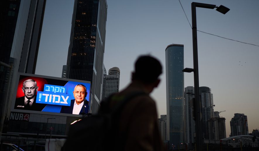 A pedestrian passes a campaign billboard featuring Israeli Prime Minister Benjamin Netanyahu, left, and his main rival, opposition candidate Gadi Eisenkot, with a message in Hebrew that reads "The race is tight," Friday, Oct. 23, 2026, in Tel Aviv, Israel. (AP Photo/David Goldman)