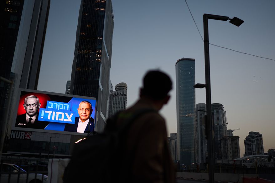 A pedestrian passes a campaign billboard featuring Israeli Prime Minister Benjamin Netanyahu, left, and his main rival, opposition candidate Gadi Eisenkot, with a message in Hebrew that reads "The race is tight," Friday, Oct. 23, 2026, in Tel Aviv, Israel. (AP Photo/David Goldman)