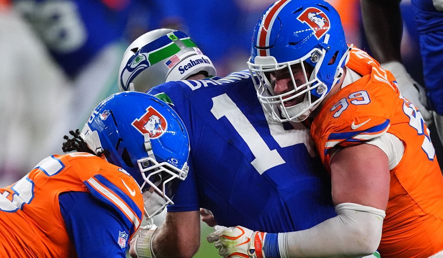 Denver Broncos defensive end Zach Allen (99) sacks Seattle Seahawks quarterback Sam Darnold (14) with Broncos linebacker Nik Bonitto, left, during the second half of an NFL football game in Denver, Thursday, Oct. 15, 2026. (AP Photo/David Zalubowski)