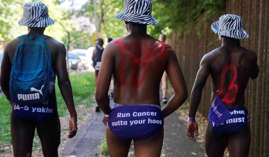 Men walk through the streets wearing only purple swim briefs to raise awareness about prostate cancer, in Johannesburg, Friday, Oct. 23, 2026. (AP Photo)