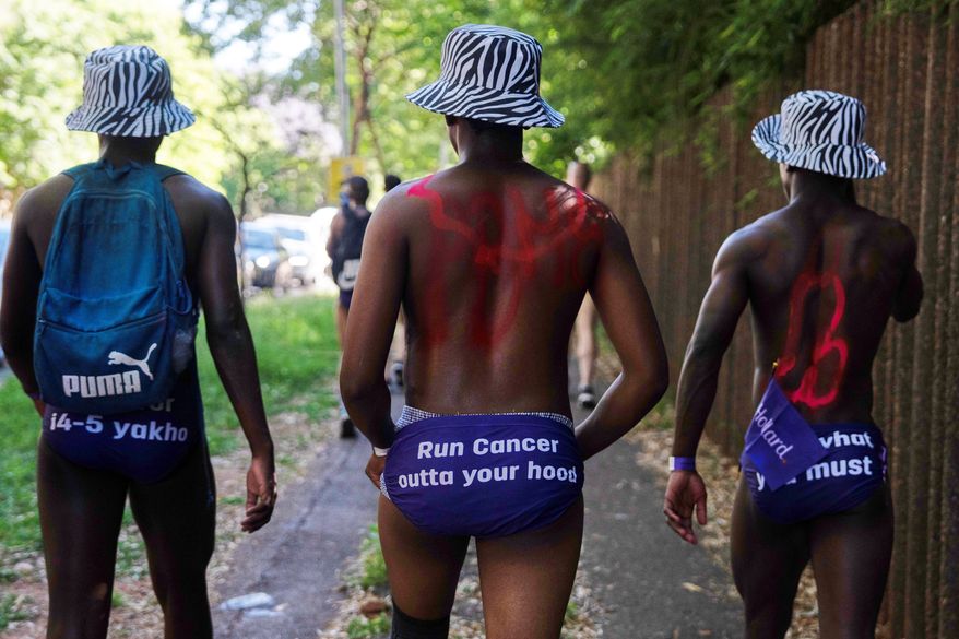 Men walk through the streets wearing only purple swim briefs to raise awareness about prostate cancer, in Johannesburg, Friday, Oct. 23, 2026. (AP Photo)