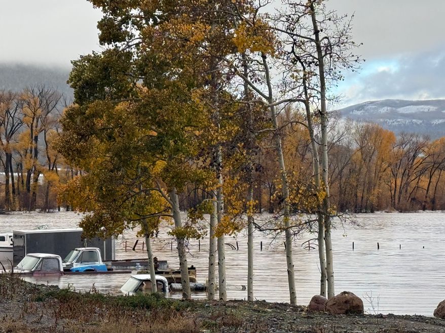 Pickup trucks are submerged along Highway 160 in South Fork, Colo., on Friday, Oct. 23, 2026. (South Fork Fire Rescue via AP)