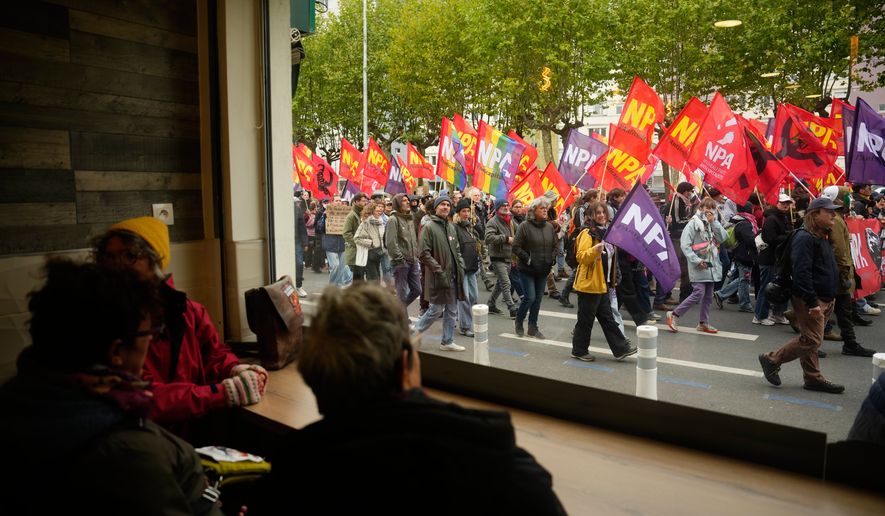 People sitting in a pub watch demonstrators during a protest on the sidelines of the far-right Rassemblement National (RN) congress in Orleans, France, Saturday, Oct. 24, 2026. (AP Photo/Teresa Suarez)