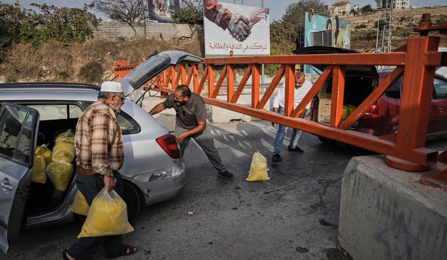 Palestinians transport bags of semolina past a military gate closed to vehicles during an Israeli army operation in Hebron, in the occupied West Bank, Saturday, Oct. 24, 2026, a day after a Palestinian shooting attack in the area. (AP Photo/Mahmoud Illean)
