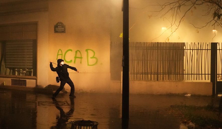 A protester throws a projectile towards police after a demonstration against rising living costs in Paris, Saturday, Oct. 24, 2026. (AP Photo/Thibault Camus)