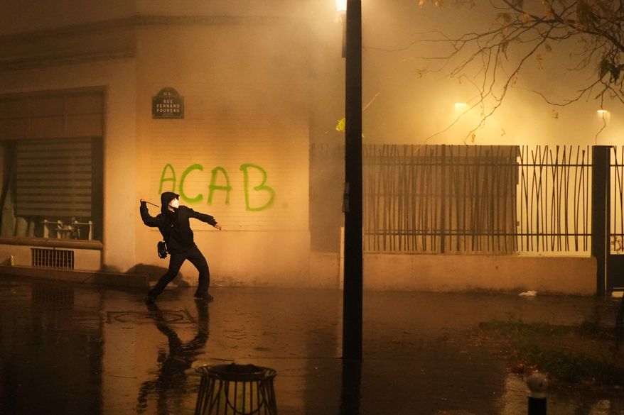 A protester throws a projectile towards police after a demonstration against rising living costs in Paris, Saturday, Oct. 24, 2026. (AP Photo/Thibault Camus)