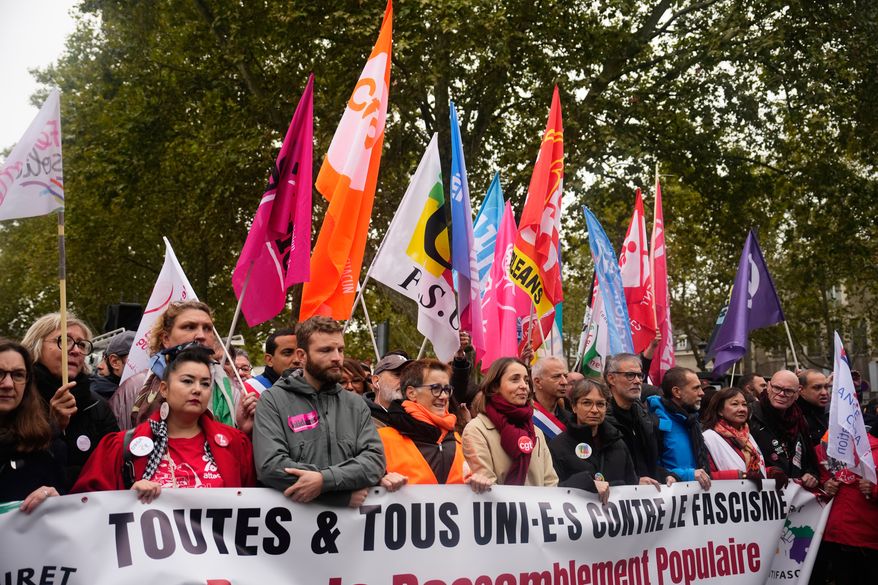 Leftists unions and political parties members hold a banner reading "all united against fascism. For the popular rally and social progress" during a protest on the sidelines of the far-right party Rassemblement National (RN) congress, in Orleans, France, Saturday, Oct. 24, 2026. (AP Photo/Teresa Suarez)