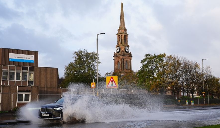 A car drives on the flooded A8 in Port Glasgow, Scotland, Sunday, Oct. 25, 2026, after Storm Boelo passed through the area. (Jane Barlow/PA via AP)