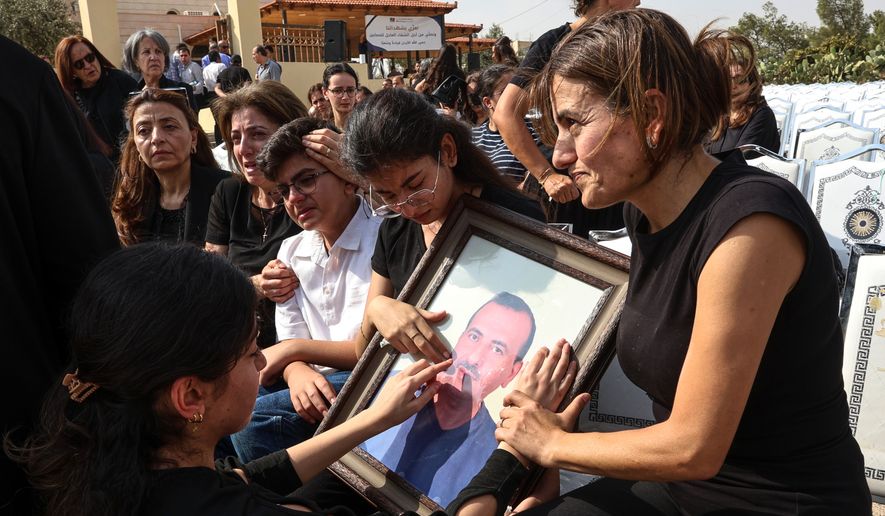 Relatives mourn as they hold a framed portrait of a victim killed in an attack on a Greek Orthodox church during a funeral ceremony in Karak, Jordan, Sunday, Oct. 25, 2026. (AP Photo/Raad Adayleh)