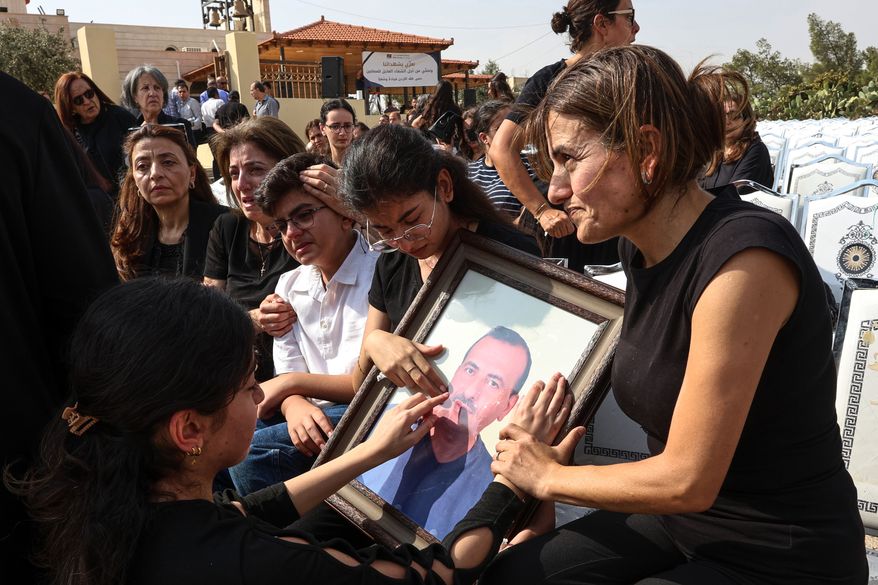 Relatives mourn as they hold a framed portrait of a victim killed in an attack on a Greek Orthodox church during a funeral ceremony in Karak, Jordan, Sunday, Oct. 25, 2026. (AP Photo/Raad Adayleh)