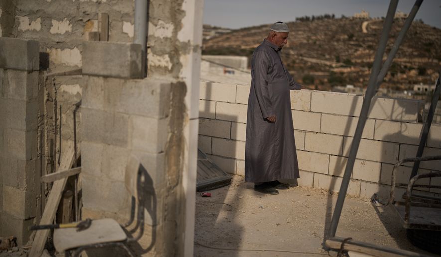 Mahmoud Tubasi stands on a rooftop near his two family's houses, which were burned by Israeli settlers in the West Bank village of Jalud, Tuesday, Oct. 20, 2026. (AP Photo/Leo Correa)